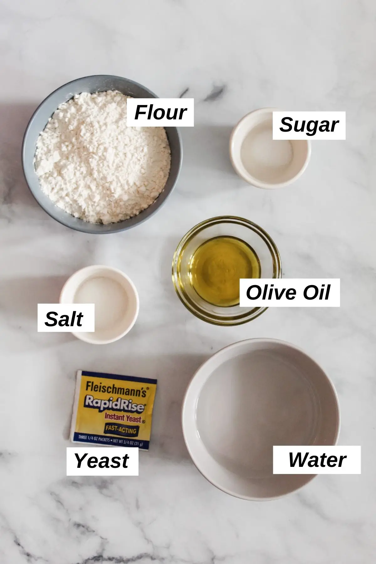 individual ingredients for pizza dough in little bowls including flour, sugar, salt, olive oil, water, and yeast