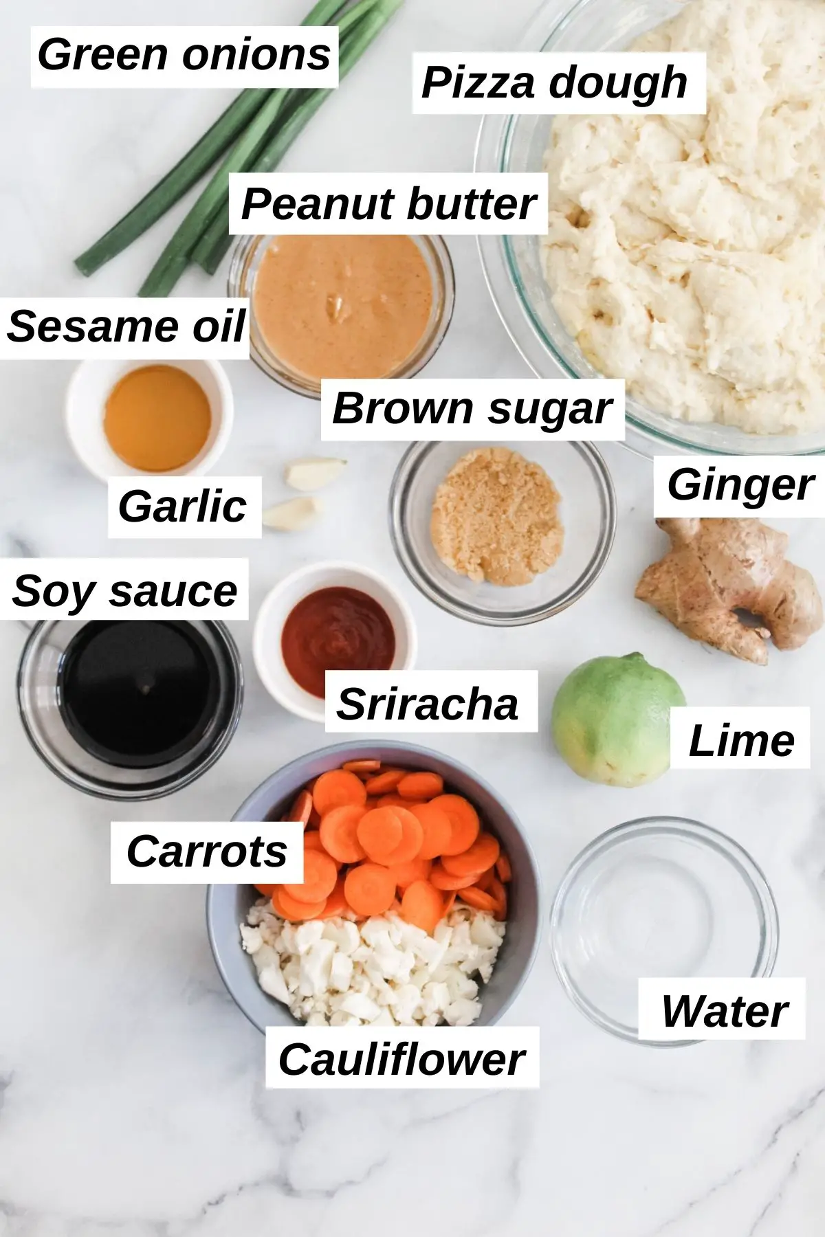 ingredients for vegan thai pizza in little bowls including peanut butter, cauliflower, sesame oil, carrots, ginger, and more