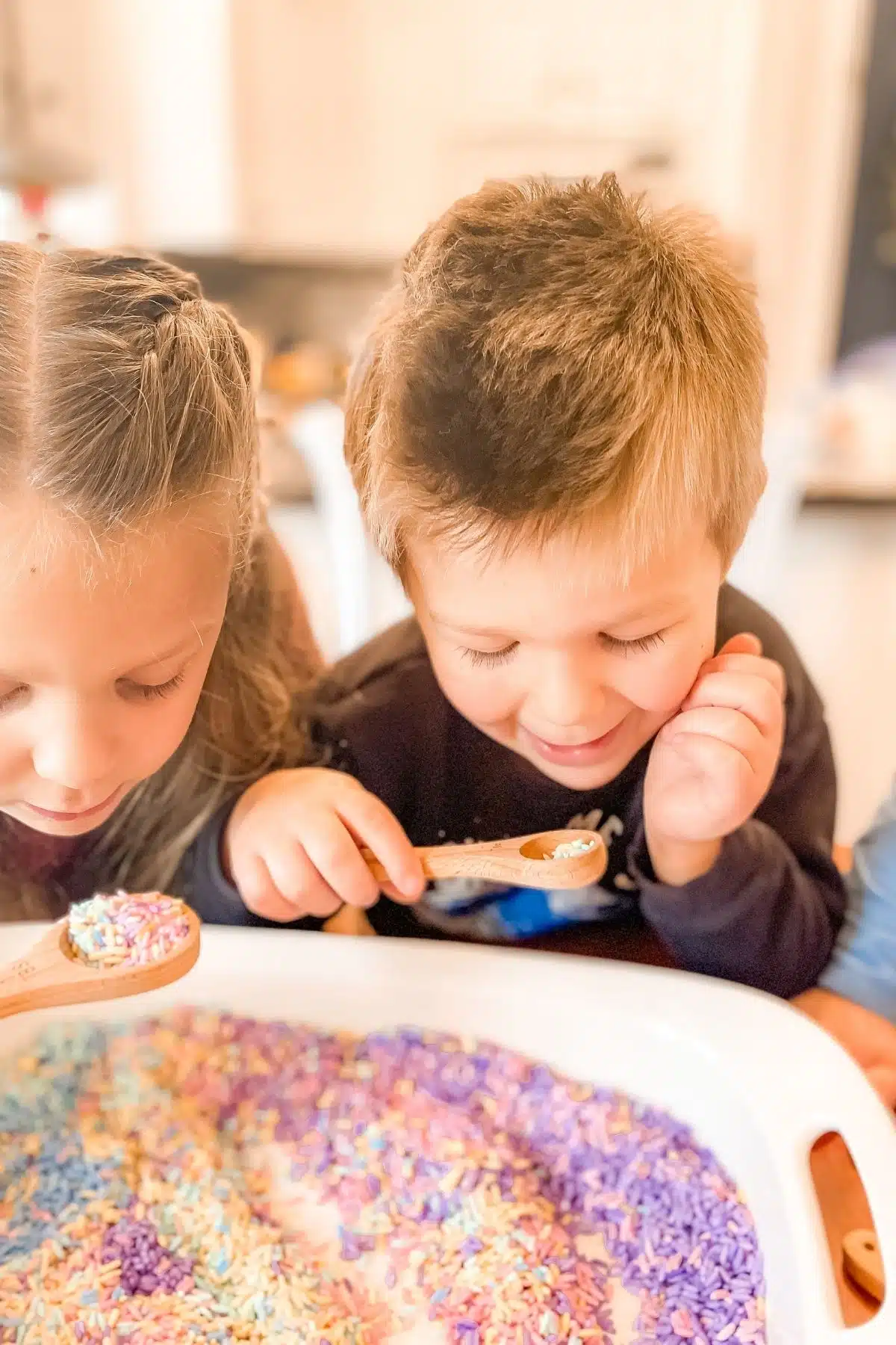 Two of my children playing with a rainbow rice sensory bin.