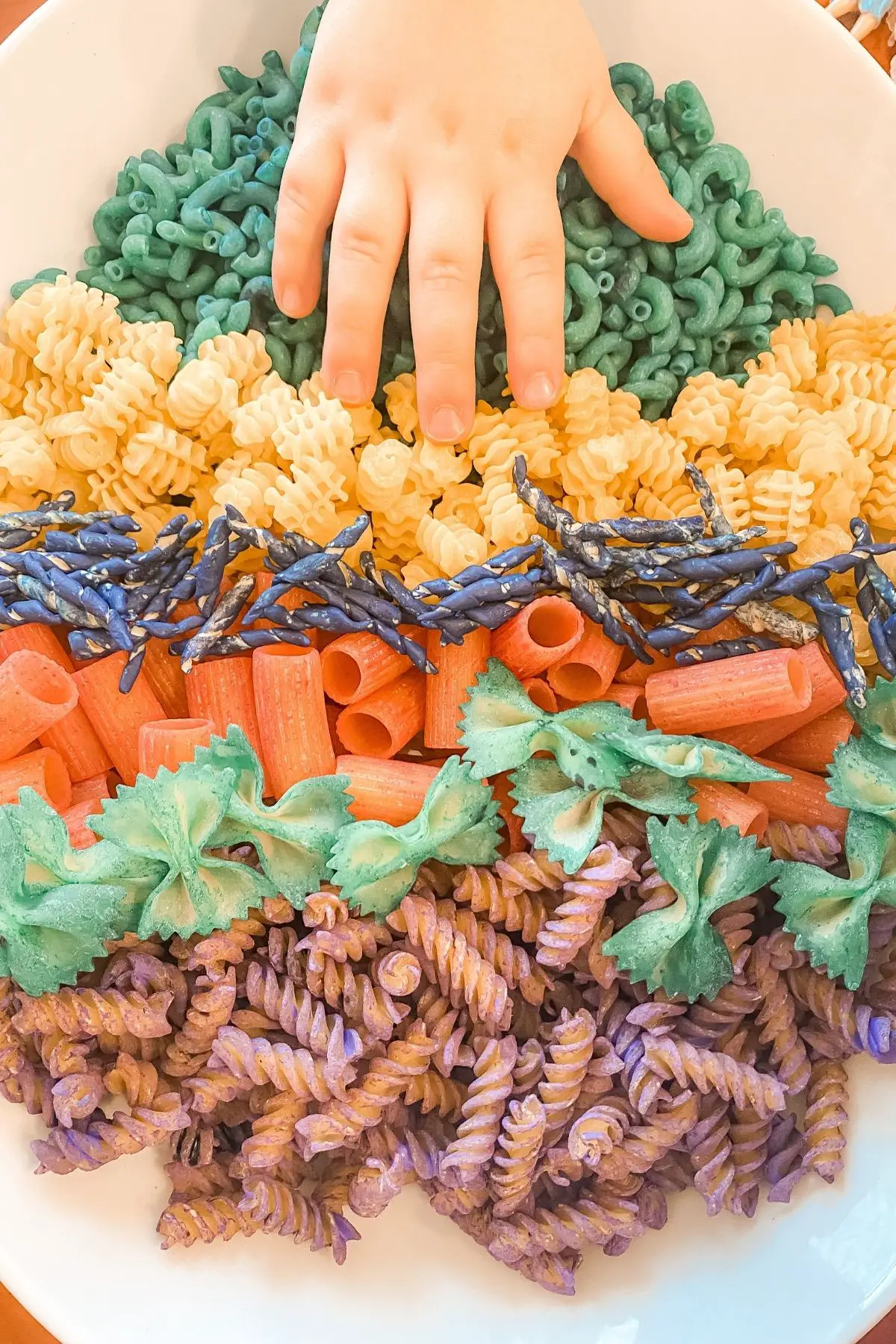 My son playing with primary colored pasta
