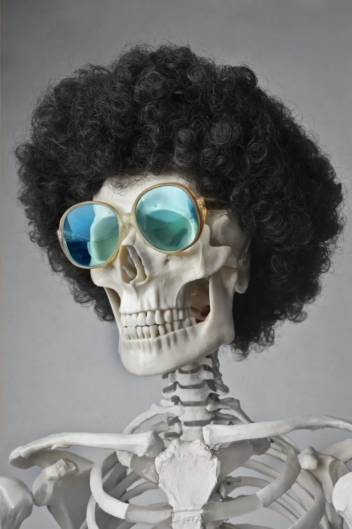 A skeleton is wearing an afro and blue sunglasses.