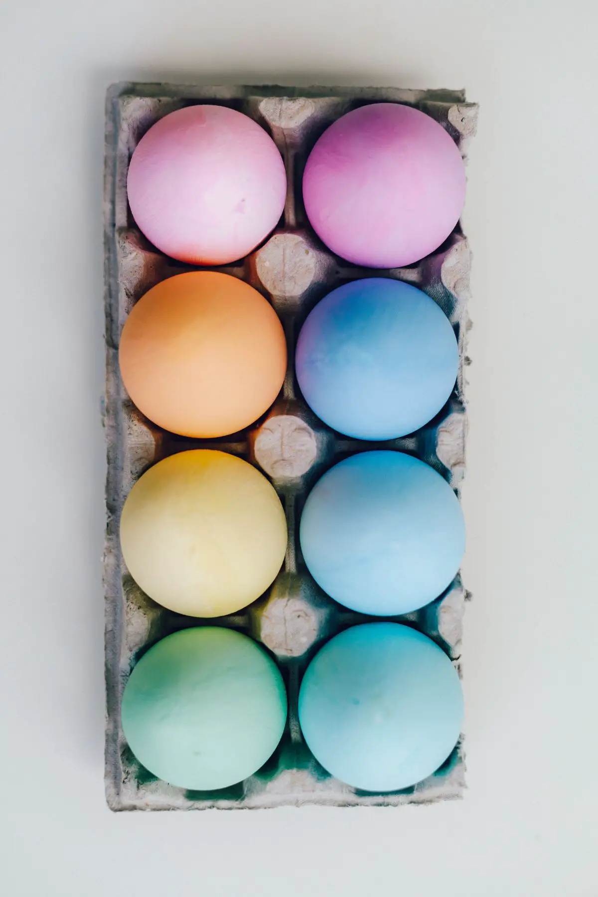 Eight colorful eggs in a carton.