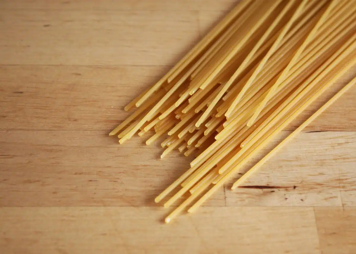 A closeup of bunch of dry spaghetti with a wood floor background.