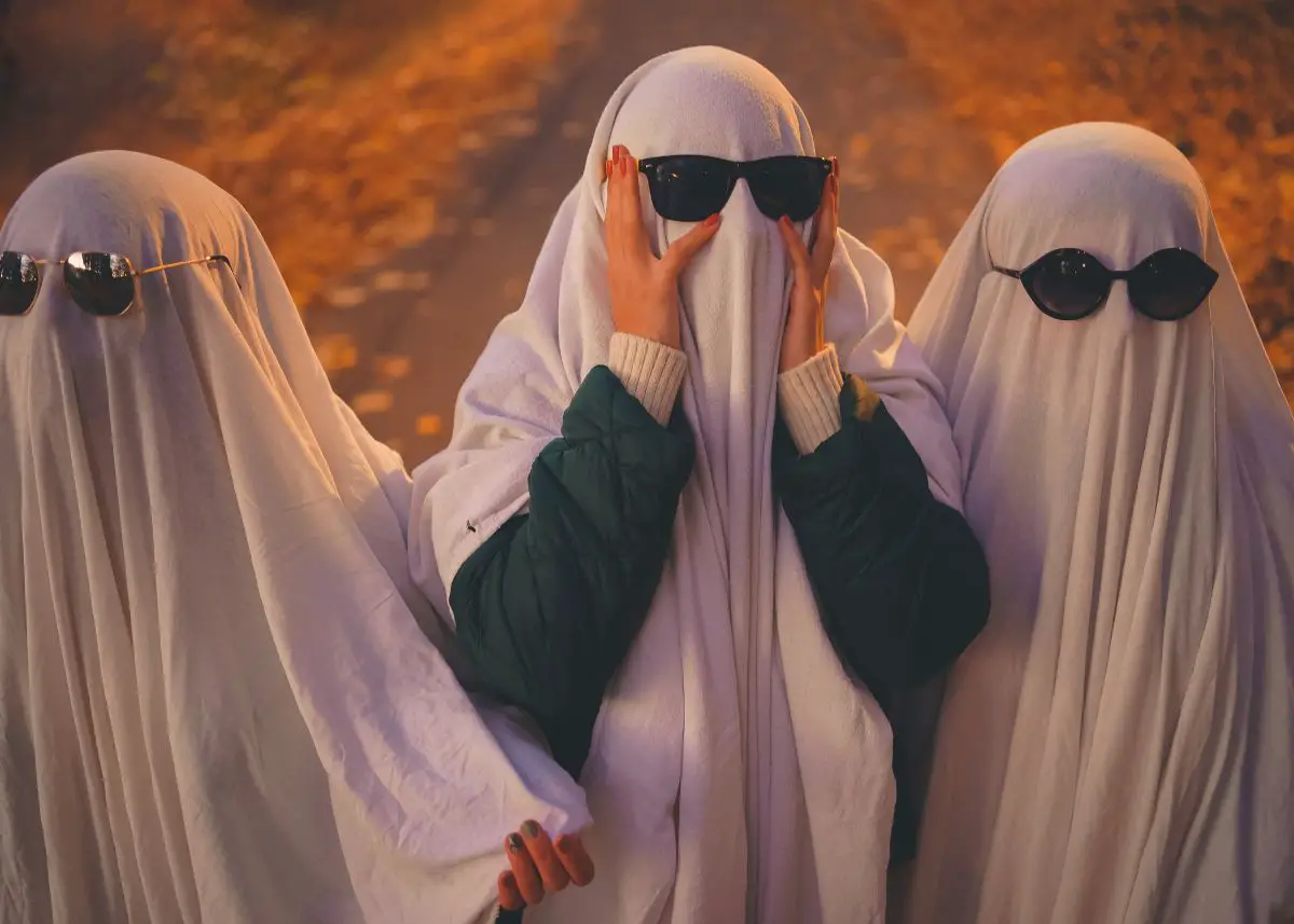 Three kids dressed as ghosts are wearing sunglasses.
