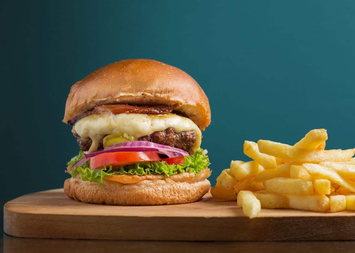 A closeup of a hamburger and fries on a wood platter. 