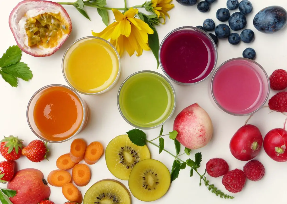 A bird's eye view of 5 smoothies and tons of fruit surround them.