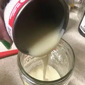 Sweetened condensed milk being poured into a mason jar