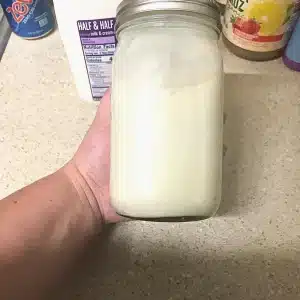 A flat lay view of all the ingredients together in a mason jar after it's been mixed, with a container of half and half in the background