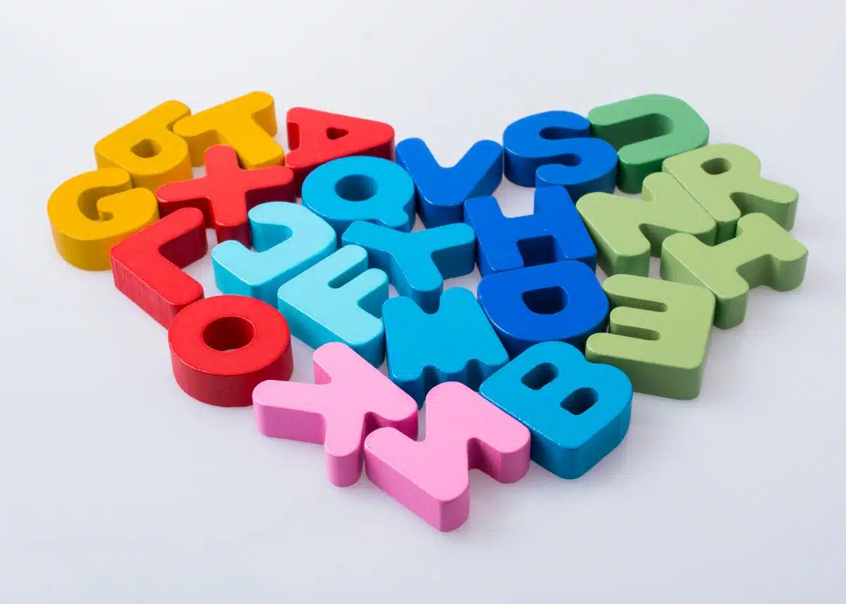 Orange, red, light blue, dark blue, green, and pink letters are arranged in a heart shape on a white background.