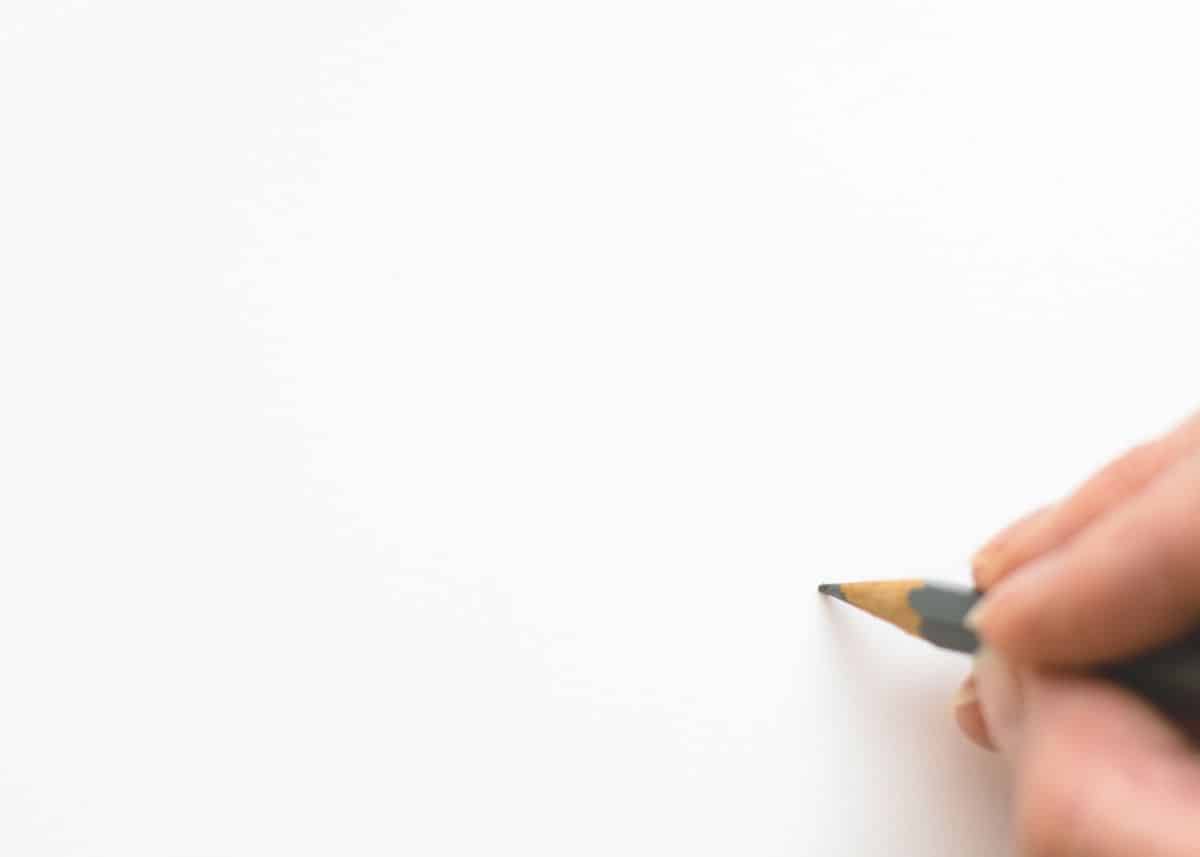 Almost all of this photo is white.  In the bottom right corner there are fingers holding a pencil.  