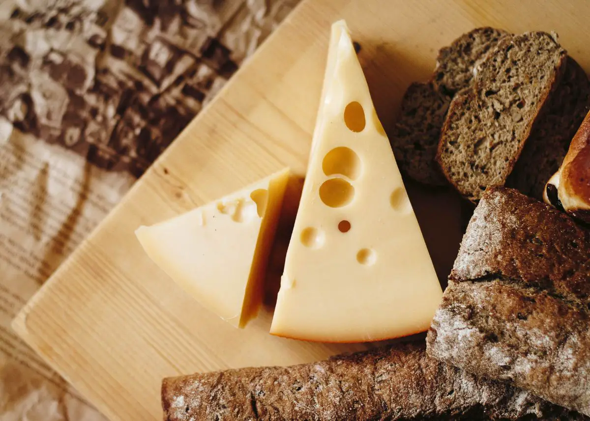 Swiss cheese and rye bread are on a cutting board.