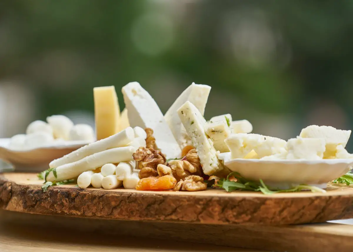 This is a cheese and nut platter.  There are lots of different cheeses.  There's a green background.