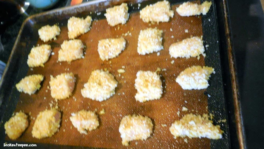breaded chicken on baking tray for baked orange chicken recipe