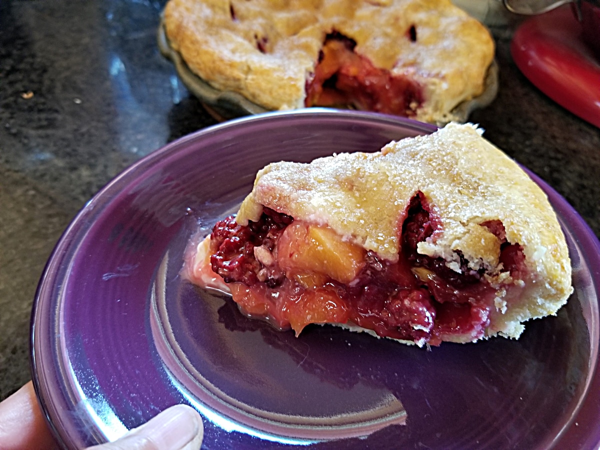 slice of peach blackberry pie on a purple plate