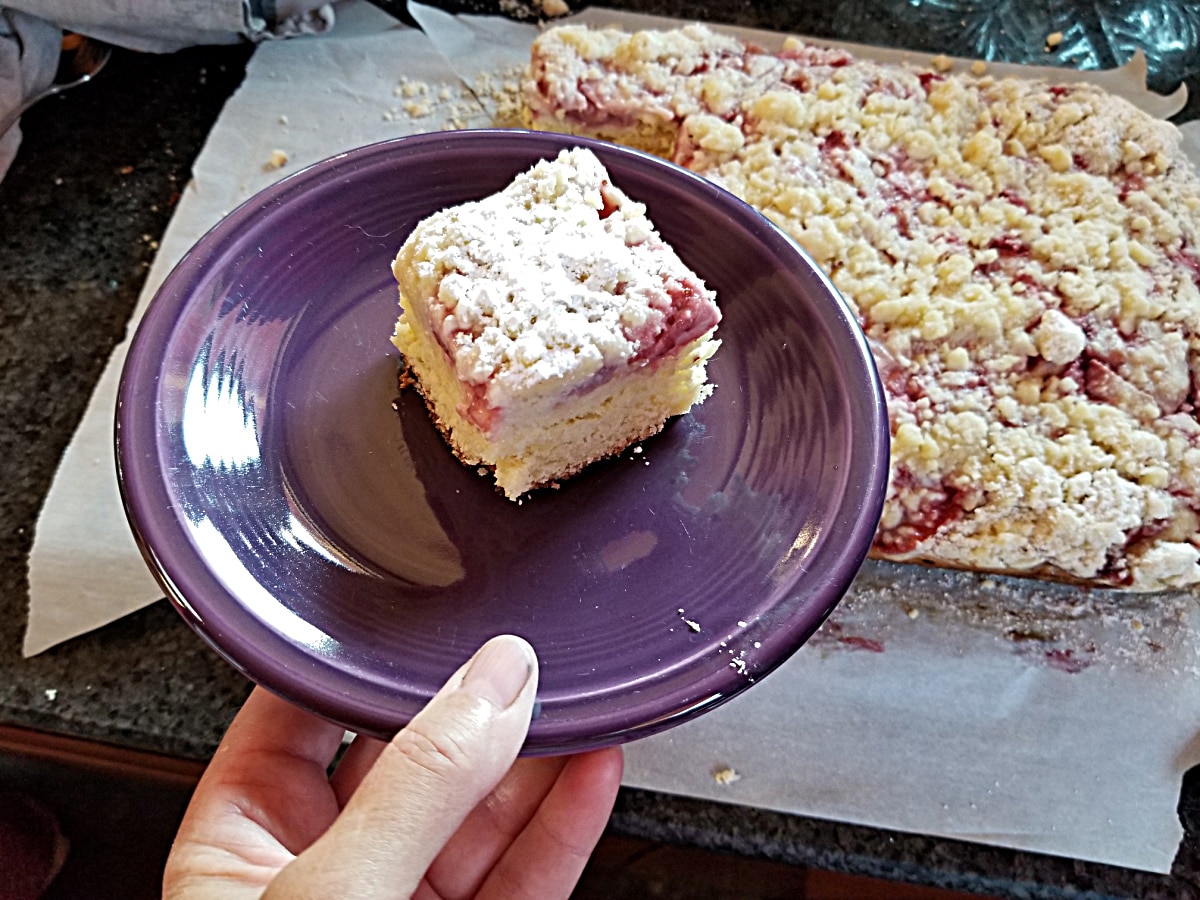 piece of coffee cake on a plate in front of cut full cake